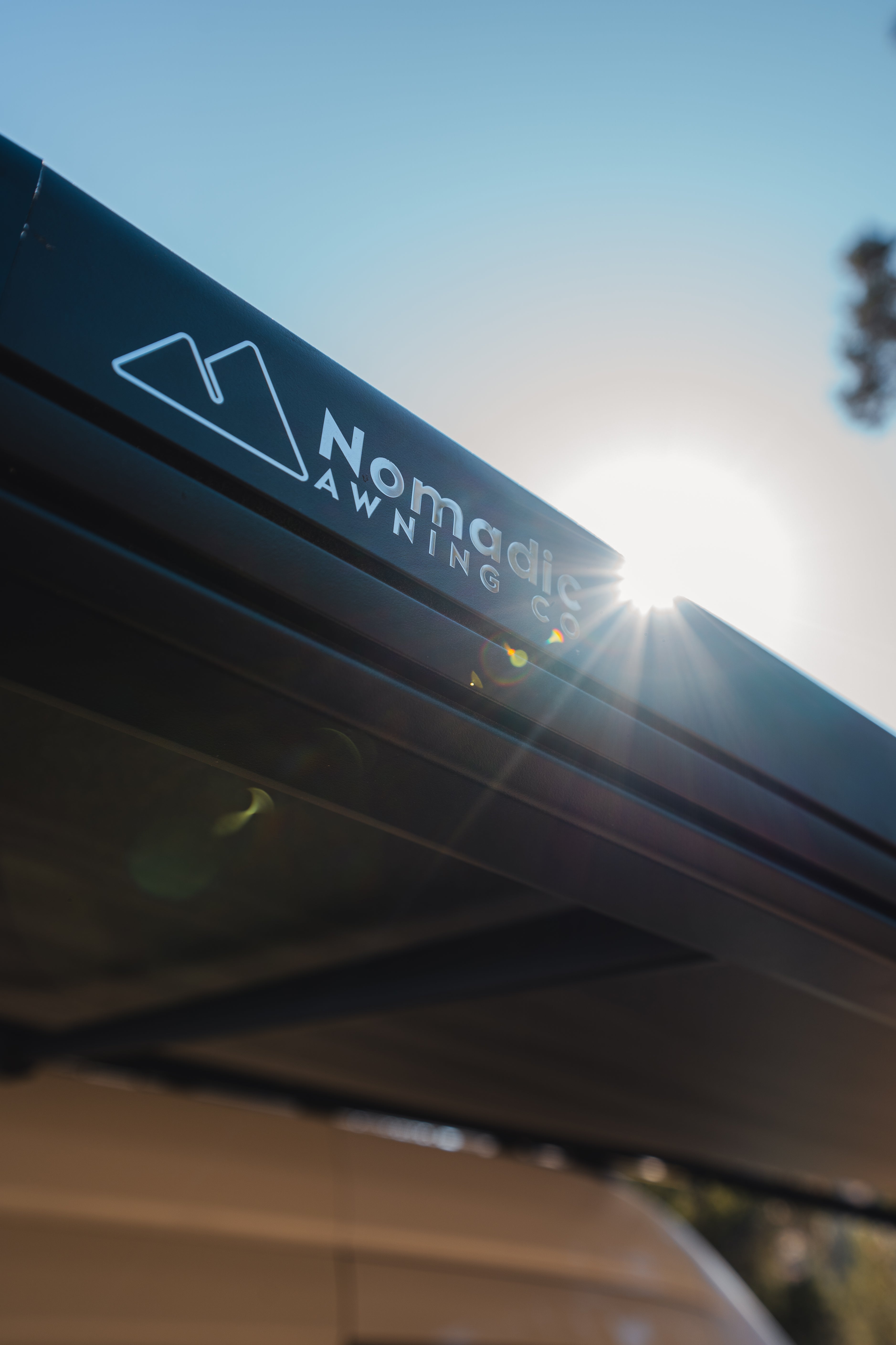 Nomadic Awning Co. logo on a vehicle roof with a blurred background