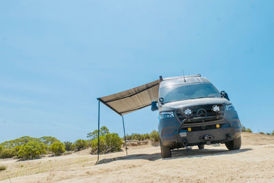 Van with a roof rack and awning in a desert landscape